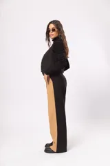 Pantalón fluido de tiro alto con bolsillos delanteros y traseros. Cierre frontal con cremallera y botón. Diseño color block negro y beige.