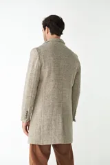 Abrigo masculino de lana color beige, con cuello con solapa, manga larga y forro interior. Tiene bolsillos laterales y cierre frontal con botones.
