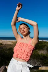 Crop top color salmón, fruncido con elásticos y tirantes finos. Detalles de volados en los bordes superior e inferior.