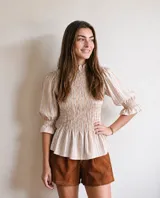 Blusa de algodón con estampado de rayas multicolor, cuello alto con volado, mangas abullonadas con puños fruncidos y cuerpo con frunces elastizados.