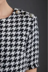 Blusa de poliéster con estampado pata de gallo en blanco y negro, de corte recto y mangas cortas con volados.