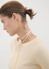 Remera de manga larga en tejido de punto fino color amarillo claro, con cuello barco y tiras finas decorativas para atar en el cuello.