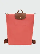 Mochila Longchamp modelo Le Pliage Original en tamaño M, color verde oscuro. Presenta solapa y asas de cuero marrón con cierre de botón a presión, correas ajustables de tela y cierre superior con cremallera.