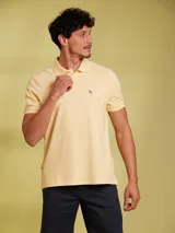 Remera polo color amarillo claro de corte clásico, con cuello y mangas acanaladas, cierre de dos botones y logo bordado en el pecho.