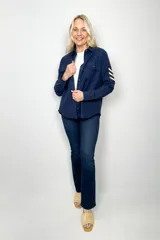 Sobre camisa azul marino de algodón con cierre de botones, dos bolsillos frontales con solapa y detalle de galones en color beige en las mangas.