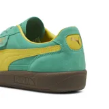 Championes Puma Palermo confeccionados en gamuza de color verde turquesa con detalles en amarillo, incluyendo la franja lateral caracteristica y el interior. Cuenta con suela de goma marrón y la etiqueta con el nombre del modelo y el logotipo de Puma en color dorado sobre el lateral externo.