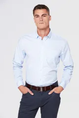 Camisa celeste lisa de vestir, con cuello clásico, manga larga, bolsillo en el pecho y corte regular.