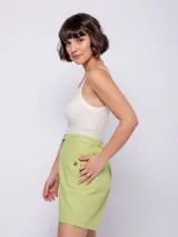 Bermuda de algodón color verde lima, de corte recto y tiro alto. Presenta cierre frontal con botones veteados, bolsillos laterales y elástico en la pretina trasera para mayor ajuste.