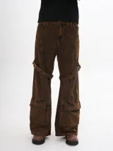 Pantalón de jean marrón con efecto gastado, corte ancho, bolsillos cargo y correas con hebillas a la altura de los muslos.
