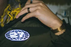 Campera puffer verde oliva con cierre frontal, capucha y logo estampado en el pecho.