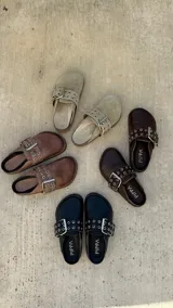 Zueco marrón de cuero con hebilla metálica ajustable, plantilla de cuero y suela de goma.