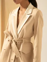 Trench color beige de lino, largo hasta la rodilla, con lazo para ajustar en la cintura y cuello y solapa en lino color crudo. Cierre con botones de carey.