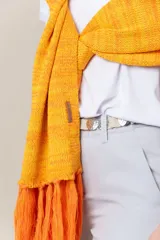 Chal de hilo artesanal color verde con detalles en gris y blanco, con flecos en los extremos y presilla para sujetarlo.