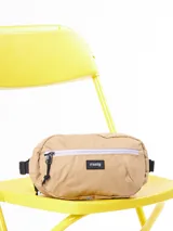 Riñonera color beige con logo de la marca Rusty en etiqueta negra cosida al frente.