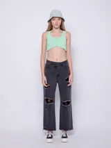 Top blanco de tela texturada, sin mangas y con cuello redondo. Cuenta con cuatro botones y terminación en curva en la parte delantera.