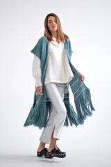 Chaleco largo de tejido de punto color azul verdoso, sin mangas y con flecos en el ruedo. Presenta calados con diseño geométrico.