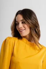 Blusa violeta de mangas largas con cuello fruncido.