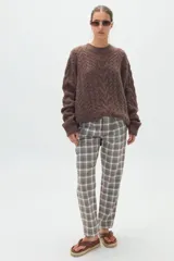 Pantalón de vestir estilo sastrero de tiro medio, con estampado a cuadros en tonos grises, blancos y marrones, de corte recto y pinzas en la cintura.