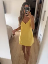 Vestido corto amarillo de lino con breteles finos y escote en V.