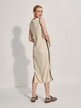 Vestido midi tejido color crema con ribete negro en cuello, sisas y ruedo. Presenta aberturas laterales en el ruedo.