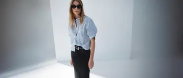 Camisa crop de corte recto confeccionada en mezcla de algodón, poliéster y viscosa. Presenta diseño de rayas verticales en azul y blanco, cuello camisero, bolsillo aplicado en el pecho y cierre delantero con botones.