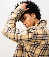 Camisa masculina de algodón con diseño a cuadros, corte oversized, cuello camisero, bolsillos frontales con solapa, cierre de botones y estampa en las mangas.