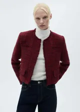 Chaqueta de corte recto y diseño corto confeccionada en tejido tweed jaspeado color bordó. Presenta cuello redondo, cierre frontal con botones, manga larga y dos bolsillos de ribete delanteros con terminaciones deshilachadas.