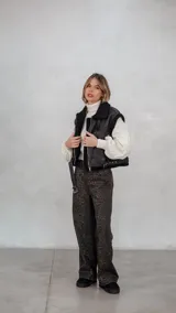 Chaleco de eco cuero negro con interior de corderito sintético, diseño oversize, cierre frontal y cinturón ajustable en el ruedo.