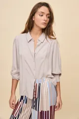 Camisa de manga larga color celeste, con cuello clásico y botonadura frontal. Presenta un calce relajado, con mangas amplias y puños anchos.