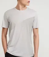 Remera deportiva de hombre, color gris claro, con cuello redondo y manga corta. Presenta un sutil efecto degradado o panel de color más claro en la zona del pecho.