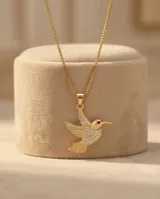 Cadena de eslabones finos con baño de oro y dije en forma de colibrí, adornado con circonias incrustadas y un detalle de piedra roja en el ojo.