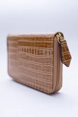 Billetera chica de cuero negro con textura tipo cocodrilo, cierre exterior, bolsillo para monedas con cierre en la parte trasera, múltiples ranuras para tarjetas y billetes, y forro rojo.