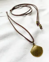 Gargantilla con cordón marrón ajustable y dije de concha dorada.