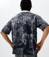 Remera de corte boxy confeccionada en tejido jacquard de poliéster con textura. Presenta cuello polo en color blanco con detalles en negro, mangas cortas y estampado frontal con lettering Bruxo y logo de Ronaldinho.