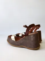 Sandalias de cuero con plataforma, color marrón con tira dorada sobre los dedos y tobillera marrón con hebilla.