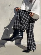 Pantalón de viyela con estampado de cuadrillé en blanco y negro. Presenta un diseño de silueta holgada con elástico en la cintura y en los puños, ofreciendo un estilo relajado y cómodo.