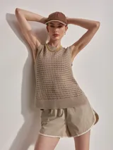 Musculosa de punto color beige con diseño calado y aberturas laterales.