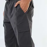 Pantalón cargo negro de corte holgado con cintura elástica y puños ajustados. Presenta bolsillos cargo en ambos muslos.