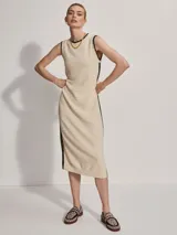 Vestido midi tejido color crema con ribete negro en cuello, sisas y ruedo. Presenta aberturas laterales en el ruedo.