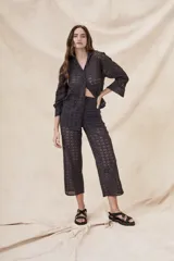 Camisa negra de algodón con bordado calado, corte oversize, cuello clásico, cierre frontal con botones y mangas largas con puños abotonados.