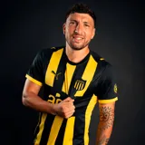 Camiseta de fútbol Puma del Club Atlético Peñarol, modelo Home. Diseño a rayas verticales amarillas y negras, con cuello redondo y detalles en amarillo en las mangas. Incluye escudo del club y logo Puma.