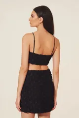 Top negro con tirantes finos y textura de flores en relieve.