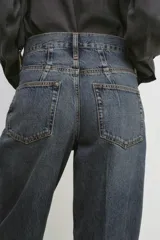 Jeans de tiro alto con corte barrel y diseño tapered, confeccionados en denim con efecto lavado y detalle de raya planchada. Presentan cintura con trabillas, cierre frontal con cremallera y botón, y bolsillos funcionales en delantero y espalda.