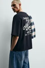 Remera de corte holgado confeccionada en algodón con interior de tejido rizo. Presenta cuello redondo, manga corta y estampados con texto en contraste en la parte frontal.