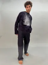 Buzo de lana merino afieltrada color negro con estampado abstracto plateado en el frente. Tiene cuello redondo y puños con forma que cubre levemente la mano. Es más largo en la parte inferior trasera.