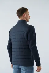 Campera azul marino con frente acolchado y mangas de felpa. Tiene cuello alto, cierre frontal, bolsillos laterales con cierre y logo de la marca en el pecho.
