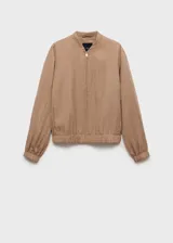 Chaqueta estilo bomber color beige, con cuello de tira, cierre frontal de cremallera, bajo y puños elásticos fruncidos y dos bolsillos laterales.