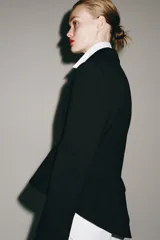 Blazer asimétrica de Zara Woman Collection, confeccionada con mezcla de lana. Presenta cuello solapa, manga larga con botones, cierre frontal con un botón y bajo asimétrico con abertura. Incluye forro interior a tono.