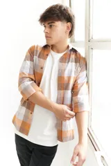 Camisa leñadora a cuadros color mostaza, blanco y gris, de manga larga y corte clásico.