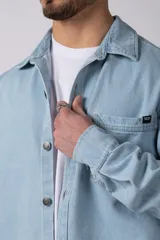 Chaqueta de denim celeste de corte relajado, con cuello clásico, cierre frontal con botones metálicos y un bolsillo aplicado en el pecho.